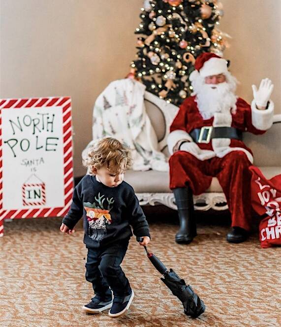 A kid playing in front of santa