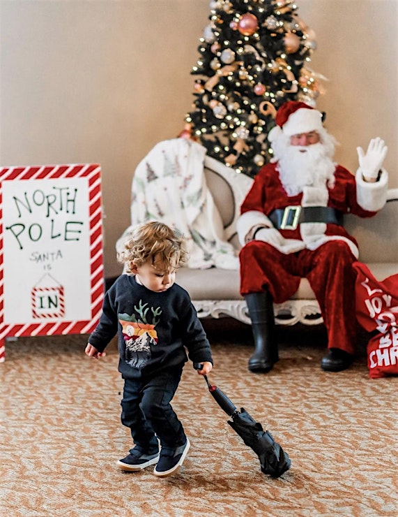 A kid playing in front of santa